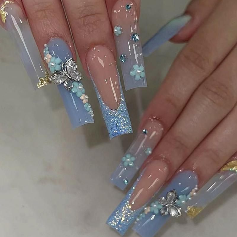 Blaues Nageldesign mit Schmetterling und Blüten